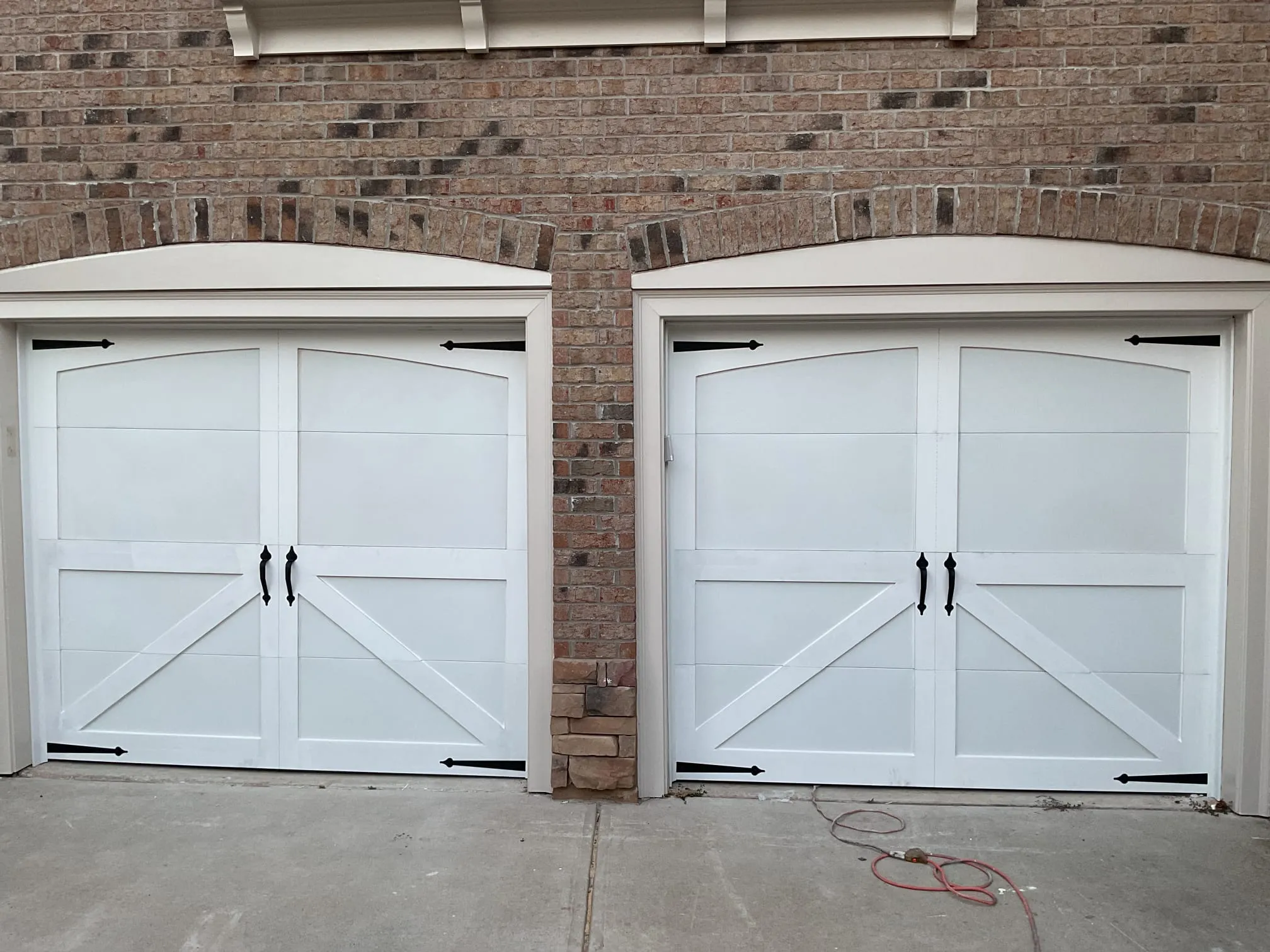 White carriage-style garage doors installed on a brick home