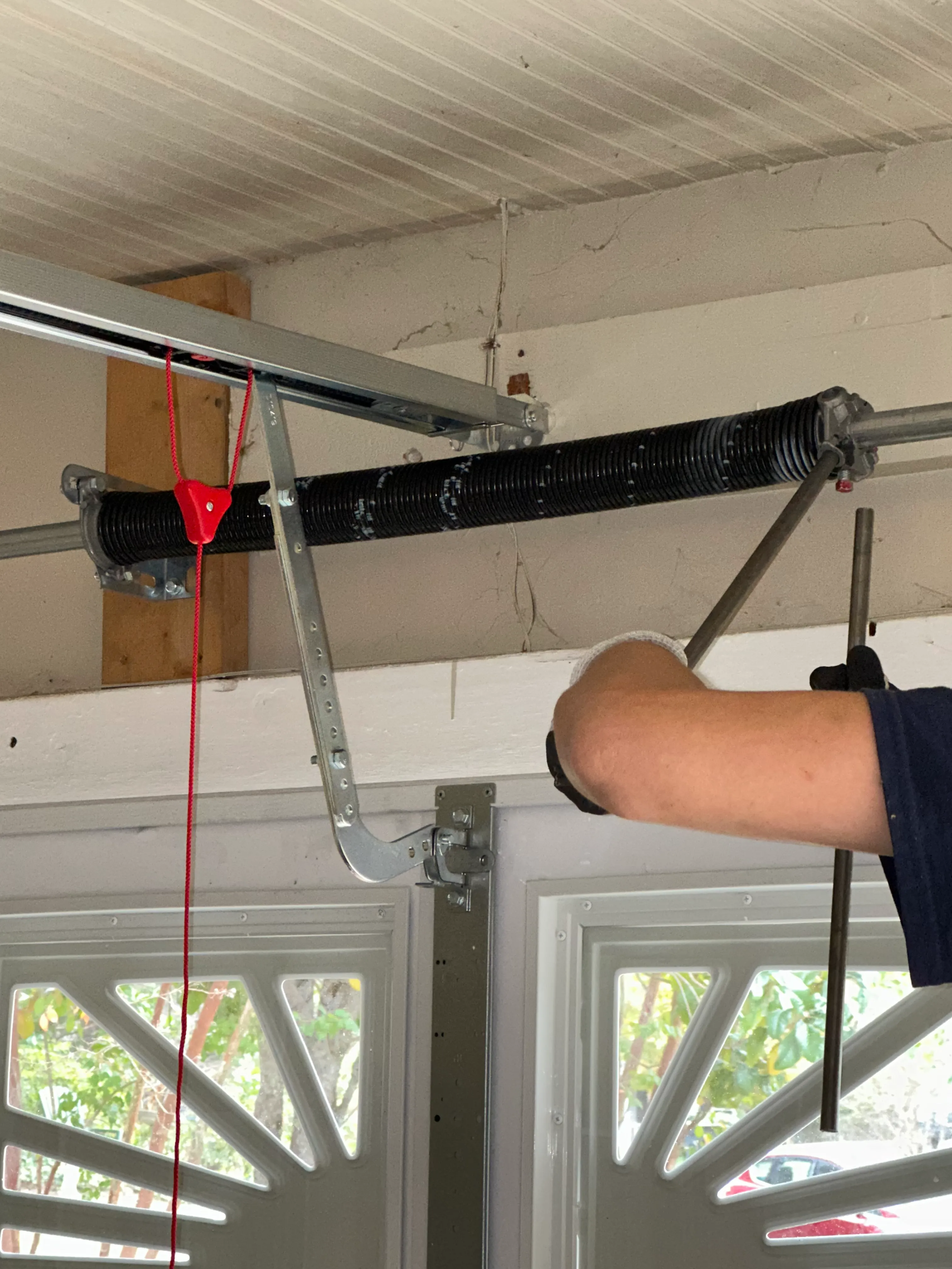 Technician completing torsion spring work above a residential garage door
